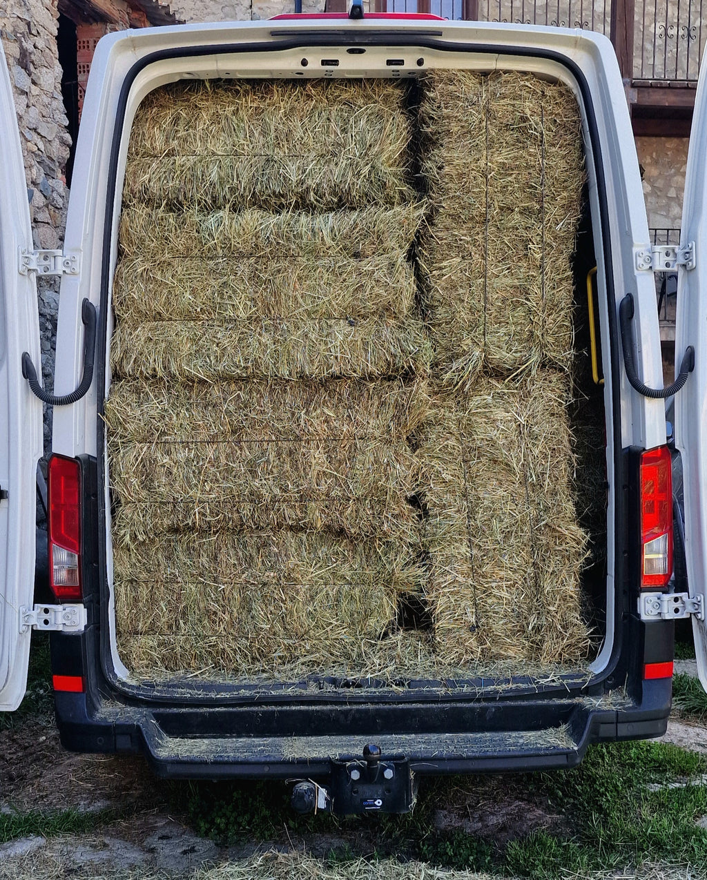 Furgoneta abierta por detrás cargada de alpacas de heno del Pirineo, lista para el reparto
