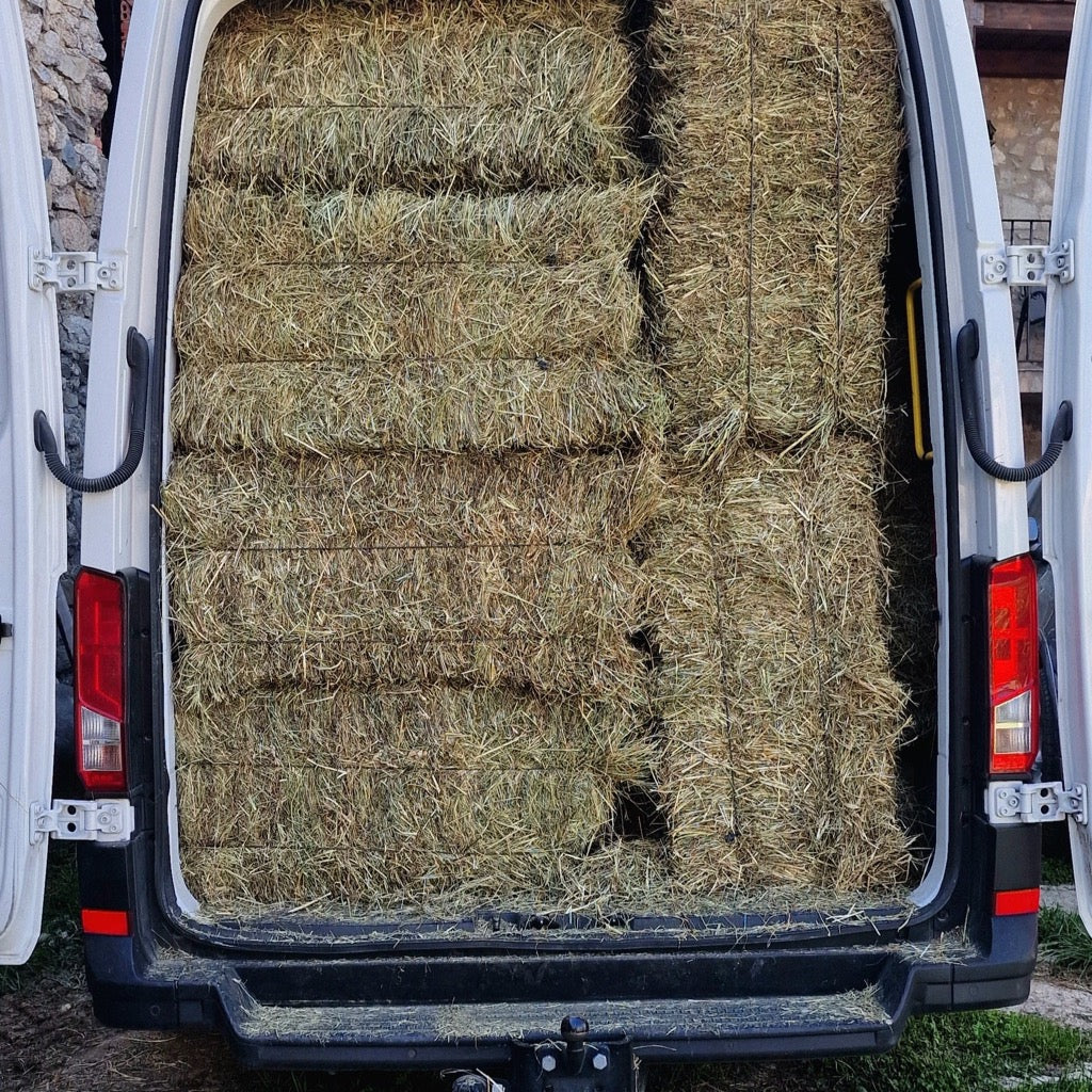 Furgoneta abierta cargada de alpacas de heno hasta el techo, lista para el reparto